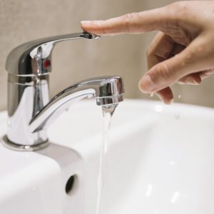 hand turning off a water faucet